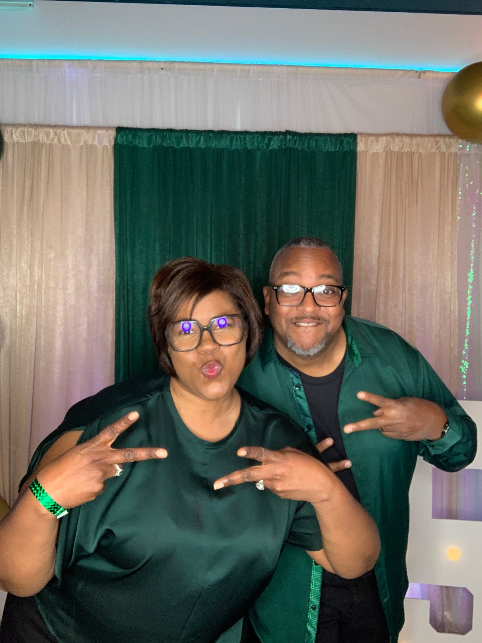 Guests striking a playful pose at an R.E.R. booth under coloured uplighting
