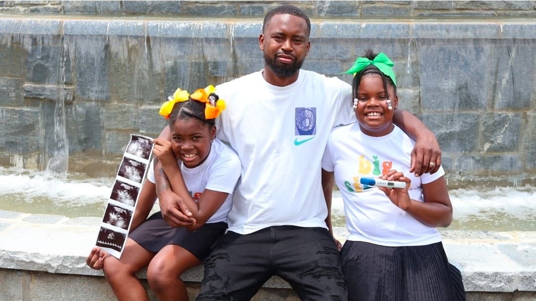 A parent seated between two children wearing matching big sister shirts at an outdoor session