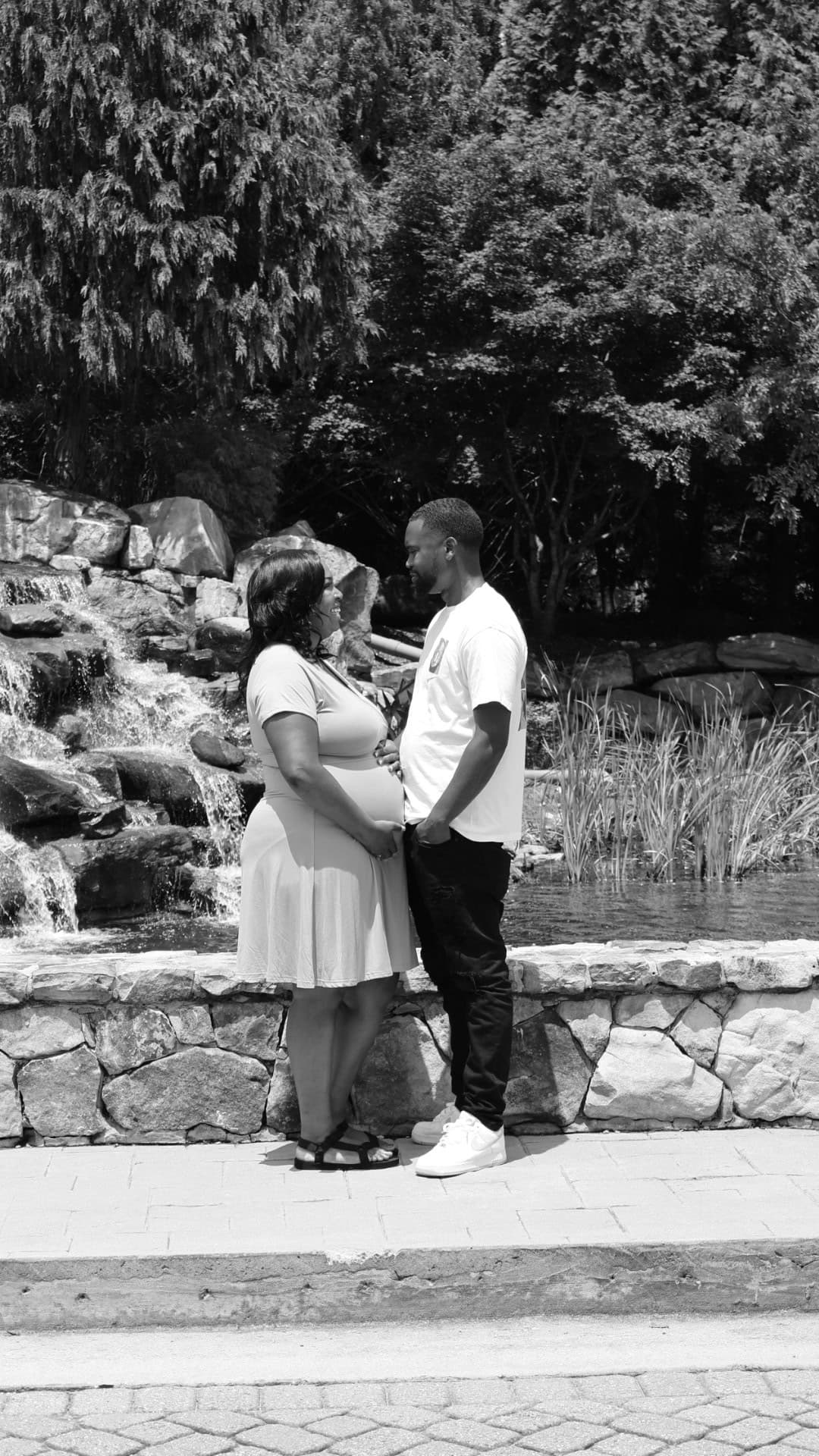 Black and white portrait of a couple standing together beside a waterfall
